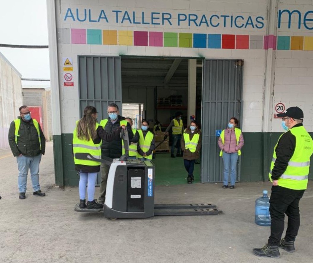 Un grupo de personas atendiendo a una demostración con una carretilla eléctrica