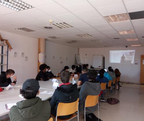 Un grupo de jóvenes sentados en una aula atendiendo a una preesntación que se proyecta en la pantalla