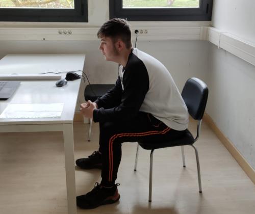 Un chico sentado en una mesa con un ordenador portátil enfrente